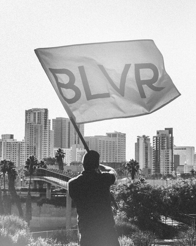 Scott Hancock, CEO of BLVR, holding BLVR flag overlooking San Diego city skyline, symbolizing belief-driven leadership and brand clarity for churches