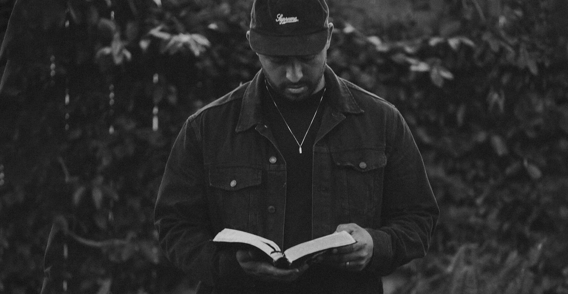Black and white photo of a Pastor of a Christian church holding and reading his bible. This is an intro to church branding on the header of the BLVR website.