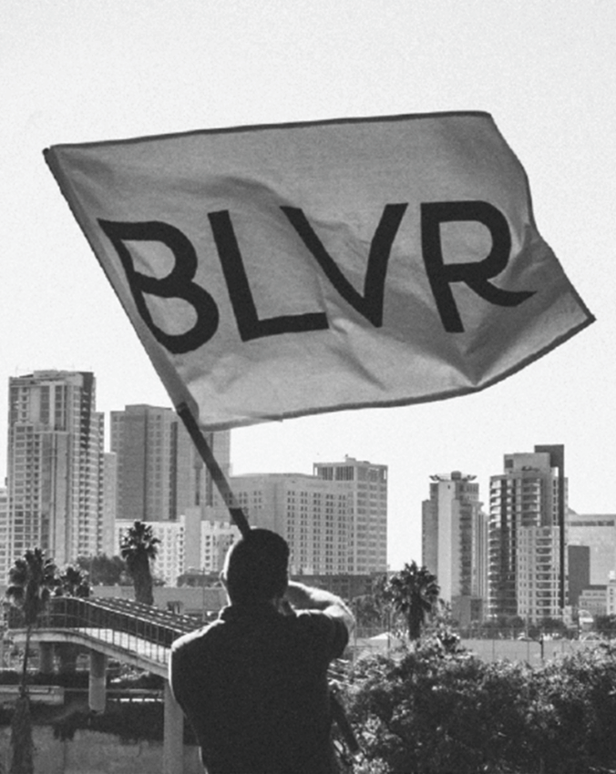 Scott Hancock, CEO of BLVR, holding BLVR flag overlooking San Diego city skyline, symbolizing belief-driven leadership and brand clarity for churches